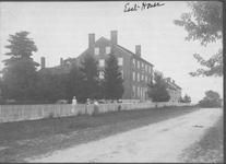 SA0417 - Photo of a large brick dwelling, also showing a fence, road and Shaker women. Identified on both the front and back.